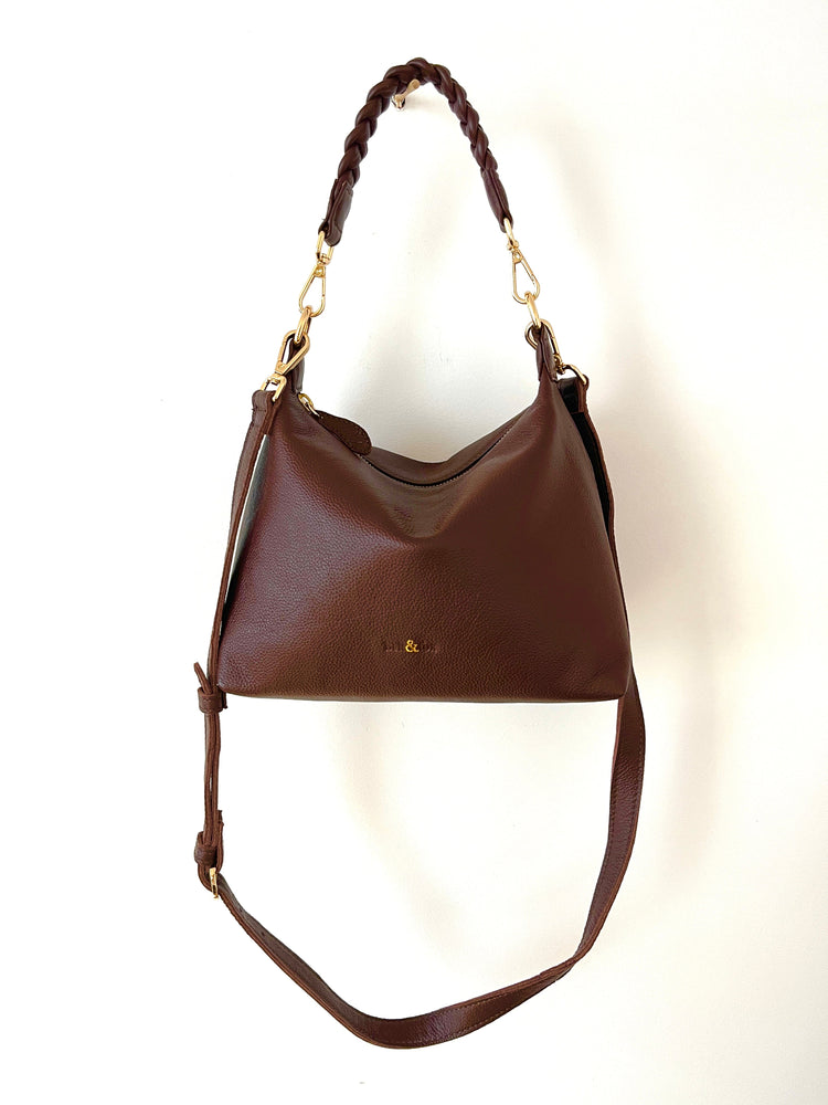 Brown leather handbag with a braided handle on a white background