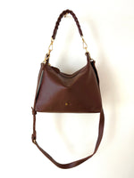 Brown leather handbag with a braided handle on a white background
